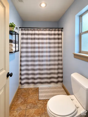 Bathroom featuring tile flooring, a tub-shower combination with a matte black rod, a recessed ceiling light, and a single-pane window