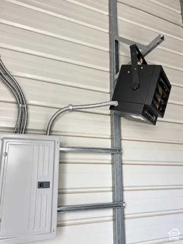 Wall-mounted industrial-style electric heater, metal panel wall cladding, and integrated electrical service panel with metallic conduit wiring