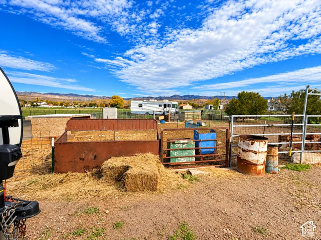 Expansive lot featuring perimeter wire fencing, metal livestock enclosures, and mountain backdrop