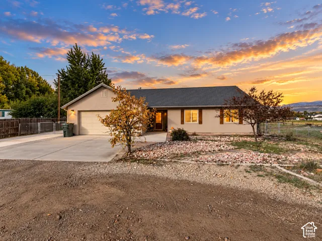 Single-story exterior featuring a stucco facade, gable roofline, attached two-car garage, concrete driveway, and xeriscape landscaping