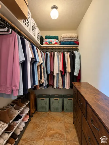 Walk-in closet featuring multi-level wood rod shelving, tile flooring, and a central flush-mount ceiling light fixture