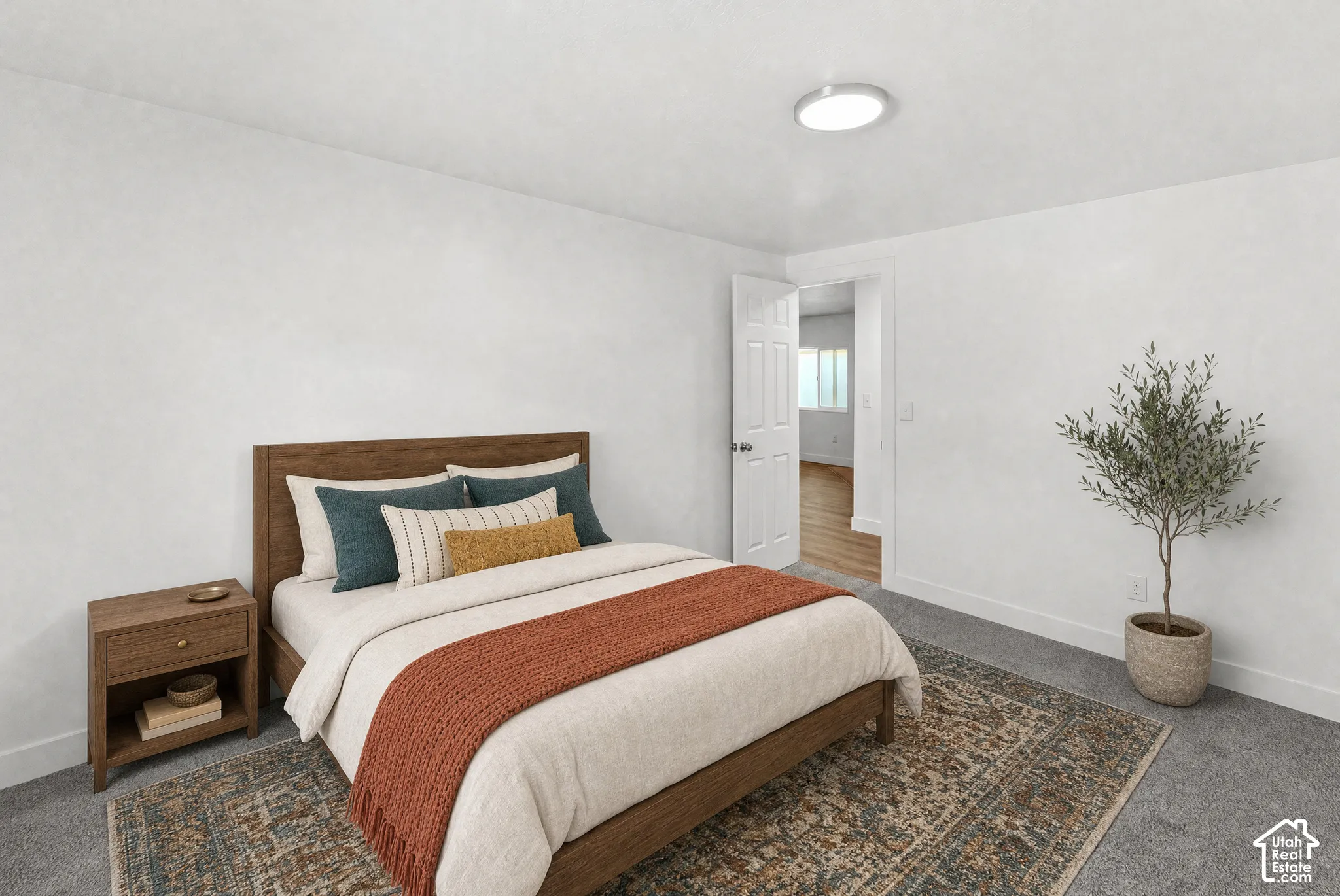 Neutral-toned walls, gray carpeting, and a white six-panel interior door with a circular flush-mount ceiling light fixture