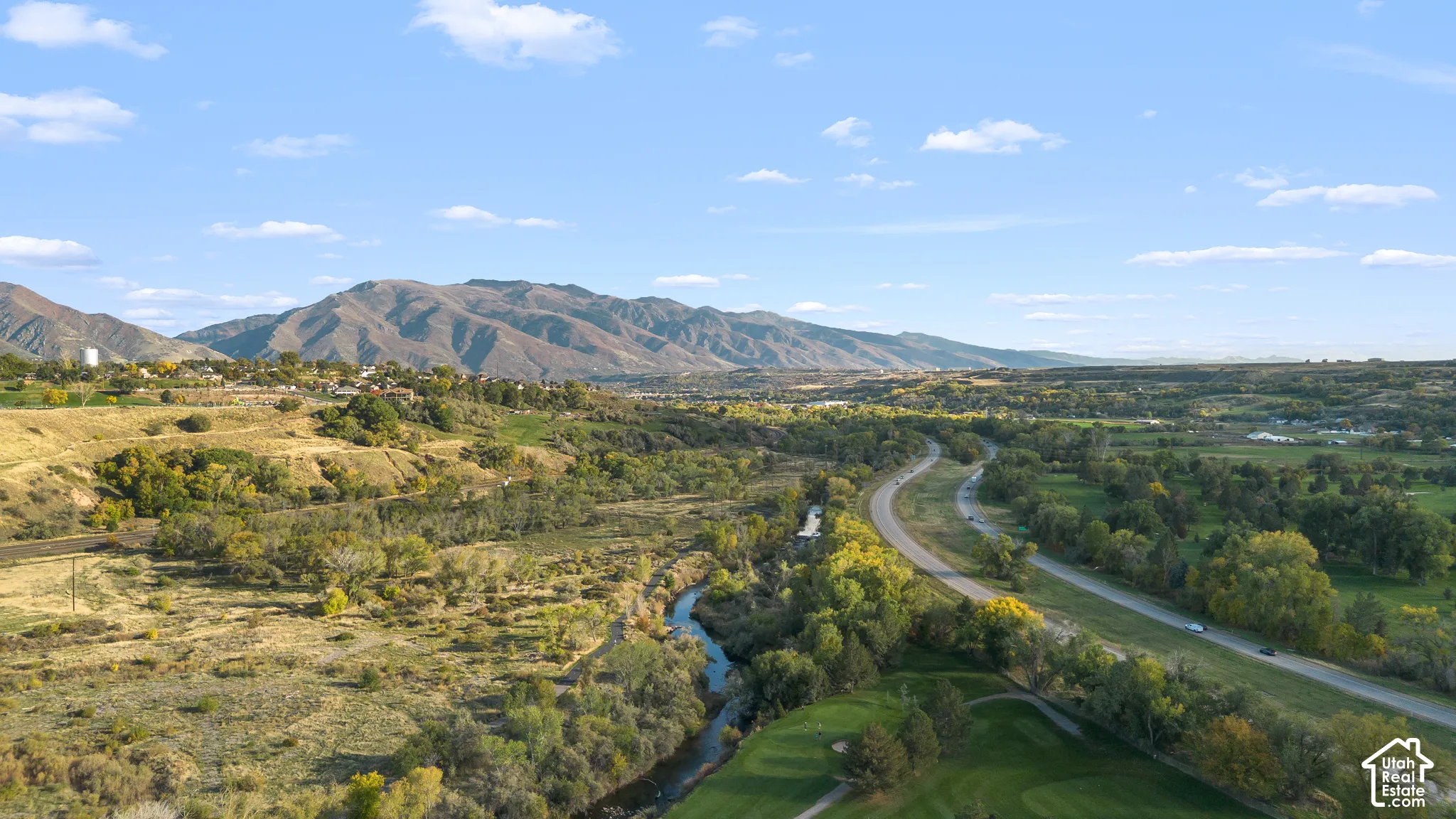 Aerial perspective featuring mountain topography, a natural water feature, mature trees, and sprawling green space