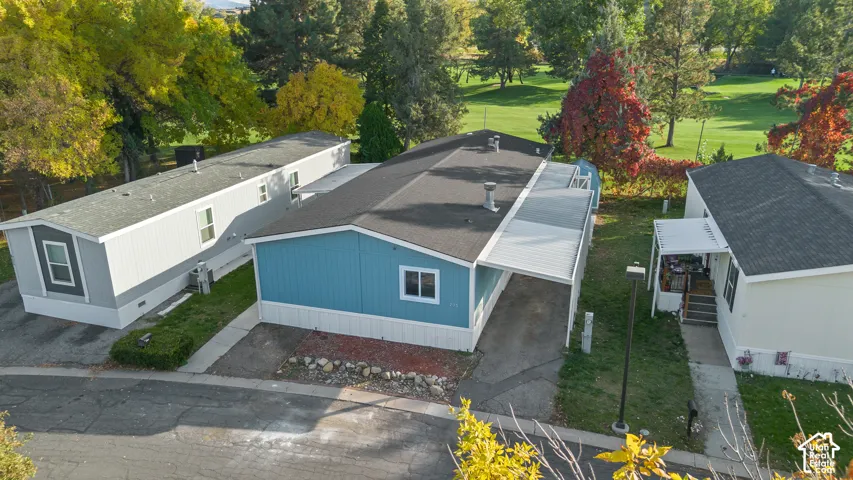 Single-story home featuring a blue exterior, shingle roofing, integrated carport, and stone-accented landscaping