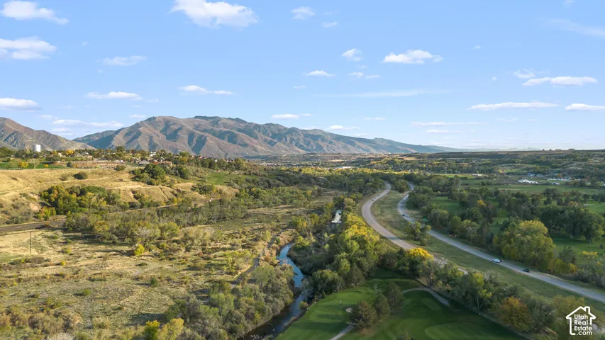 Aerial perspective featuring mountain topography, a natural water feature, mature trees, and sprawling green space