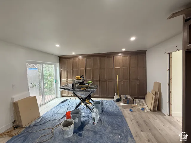 Wall-to-wall built-in cabinetry with recessed panel doors, wood-finish flooring, recessed ceiling lighting, and sliding glass door