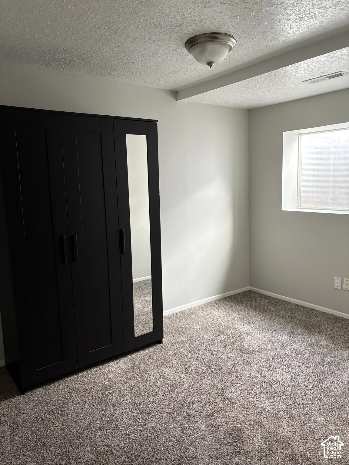 Neutral interior room featuring neutral-toned carpeting, recessed window, and a ceiling-mounted light fixture
