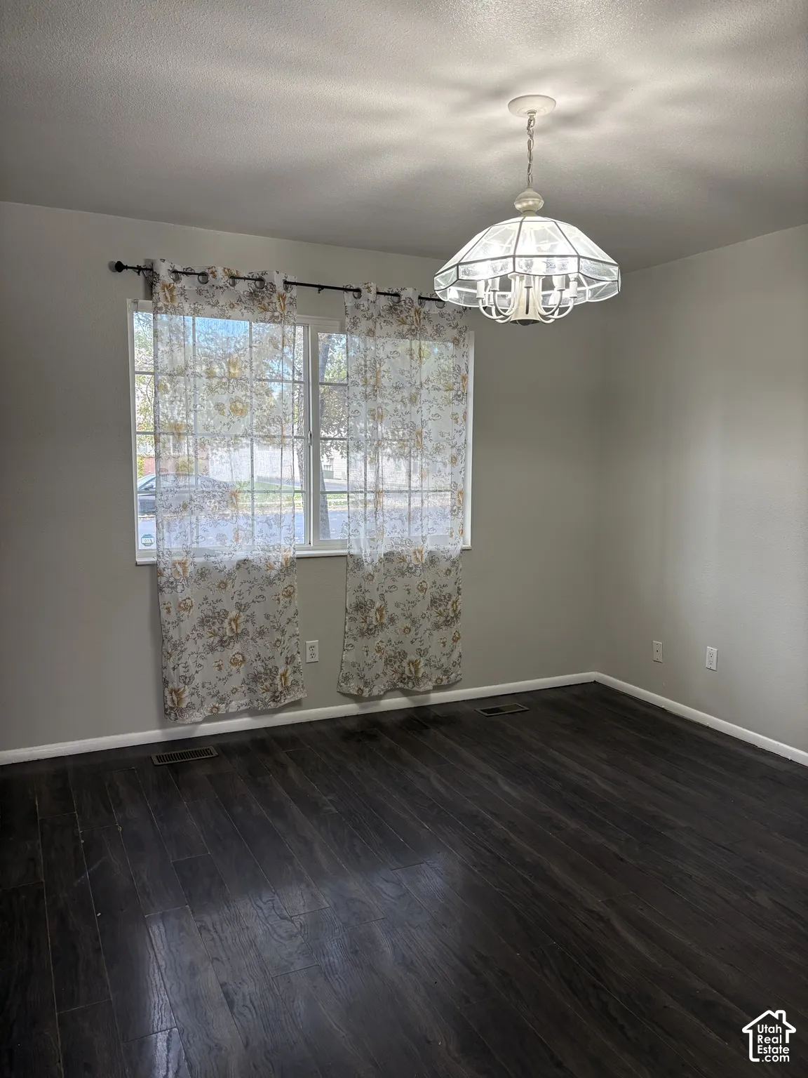 Room featuring wood-finish flooring, a multi-pane window, and an ornate, multi-arm ceiling-mounted pendant light fixture