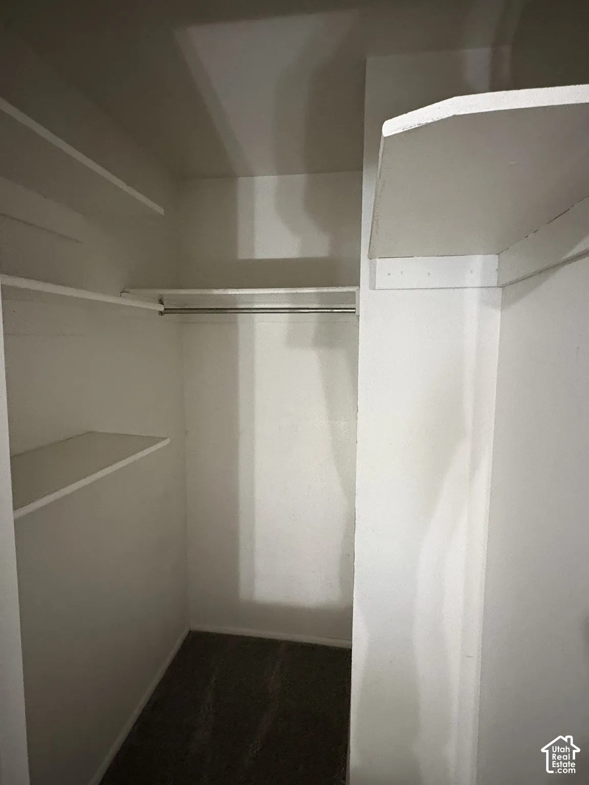 Storage closet featuring dual-level shelving and a dedicated metal garment rod