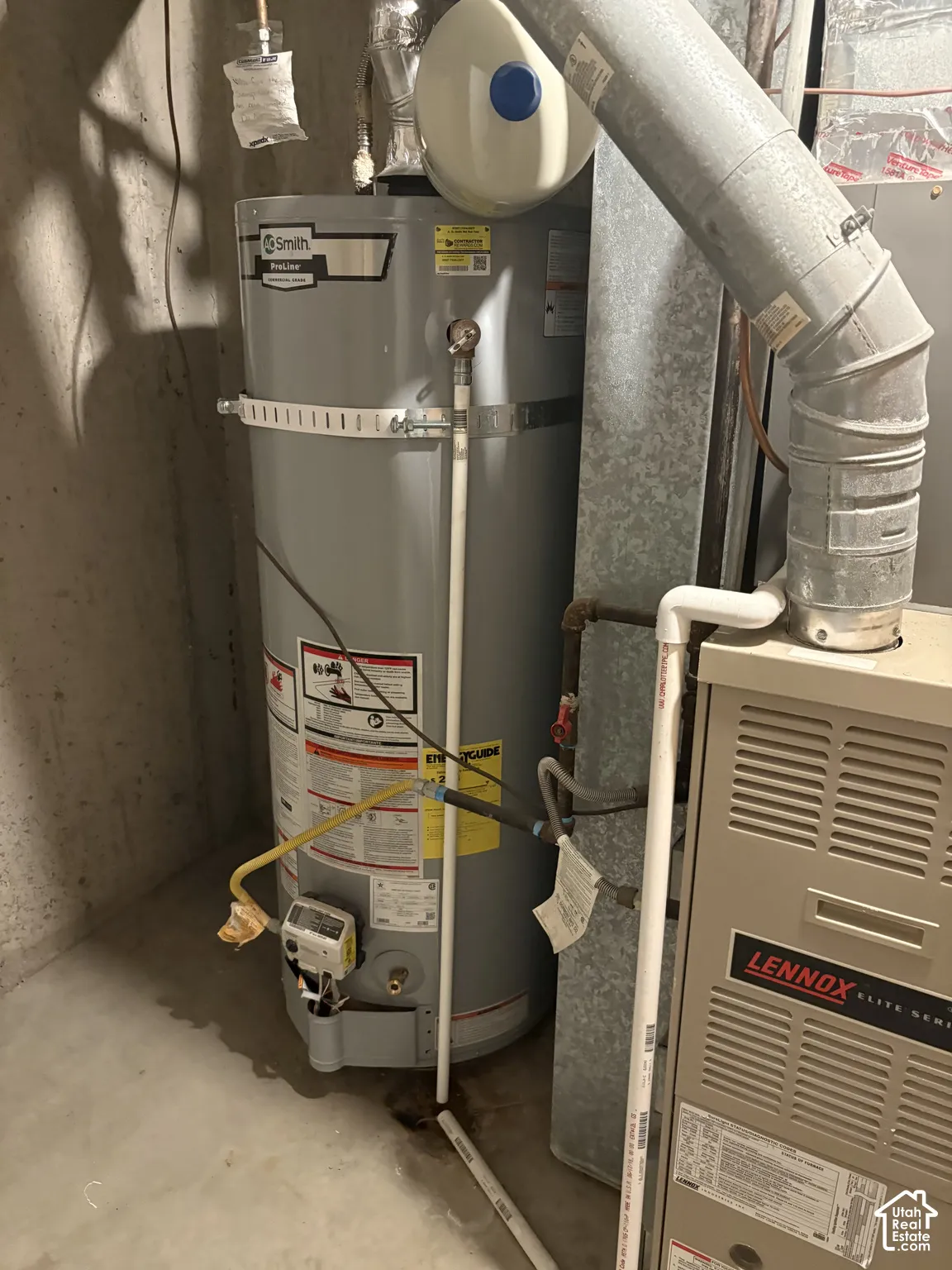 Gas-fired water heater featuring an expansion tank, metallic ductwork, and an upright forced-air furnace unit