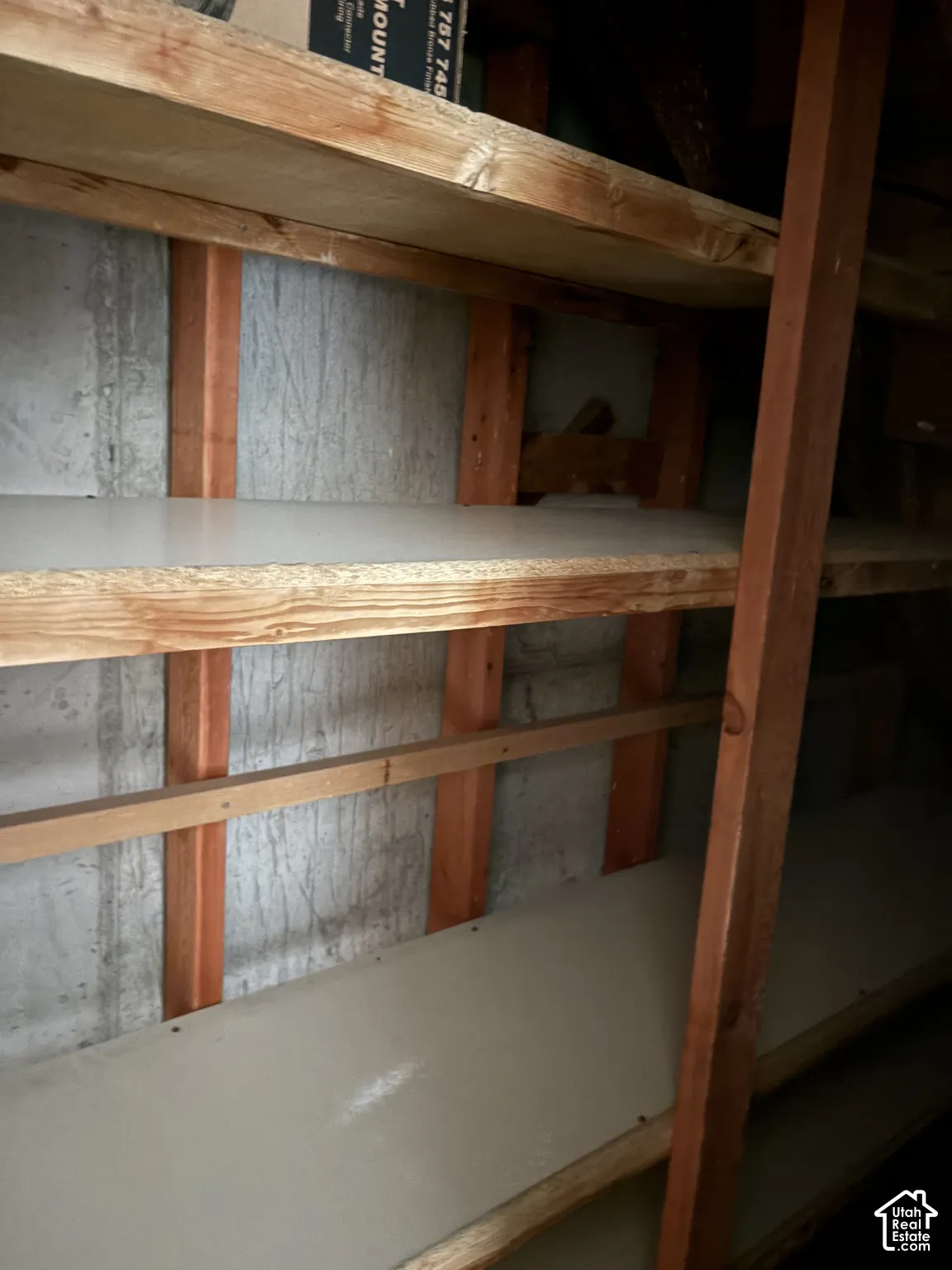 Built-in tiered wooden shelving units featuring exposed structural timber framing and poured concrete wall foundation