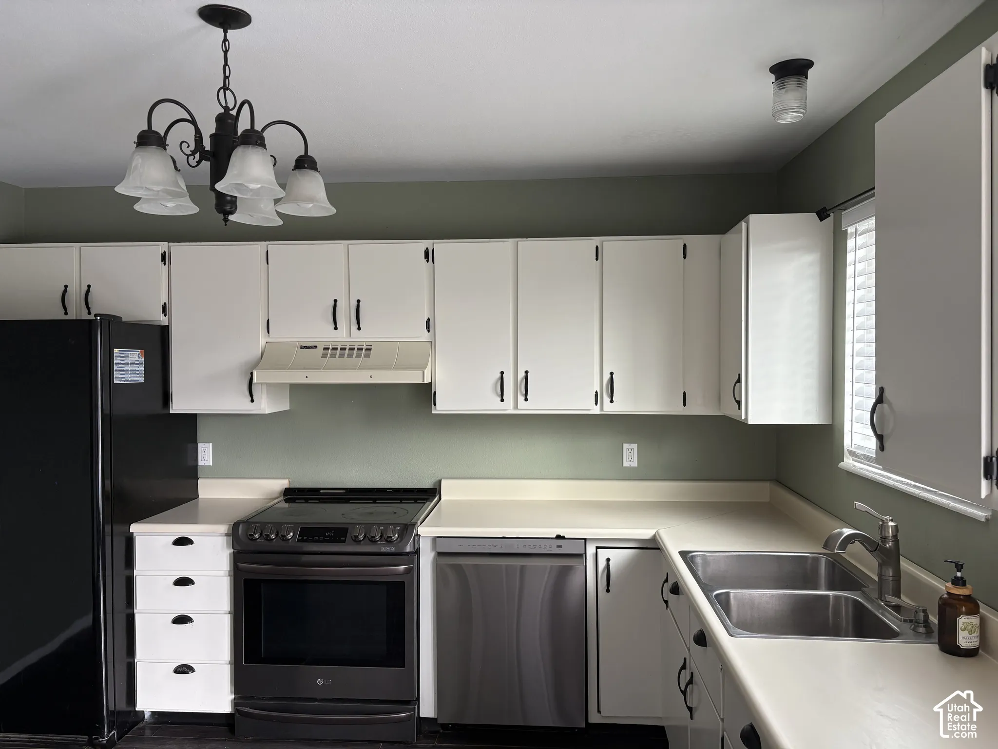 Kitchen featuring white shaker-style cabinetry with matte black hardware, stainless steel dishwasher, integrated range, and dual-basin stainless steel sink with a goose-neck faucet