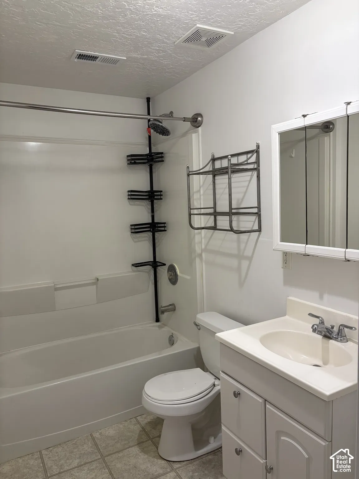 Bathroom featuring a white vanity cabinet with an integrated sink, a mirrored medicine cabinet, and a bathtub with a shower surround