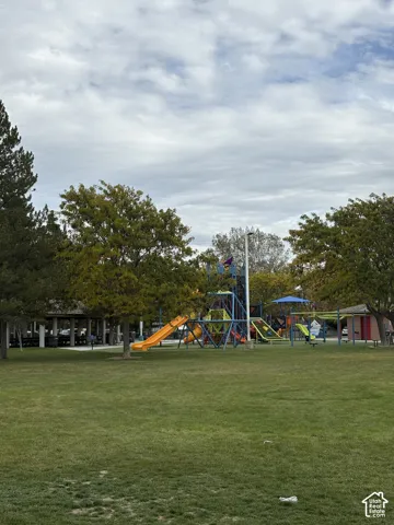Open green space featuring a playground, multiple picnic pavilions, and mature trees