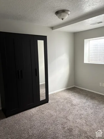 Neutral interior room featuring neutral-toned carpeting, recessed window, and a ceiling-mounted light fixture