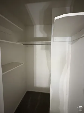 Storage closet featuring dual-level shelving and a dedicated metal garment rod