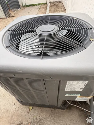 Outdoor HVAC condenser unit featuring a metal fan guard, side ventilation louvers, and a solid gray exterior housing