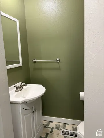 White vanity cabinet with an integrated white sink, brushed nickel faucet, wall-mounted mirror with a white frame, and tiled flooring