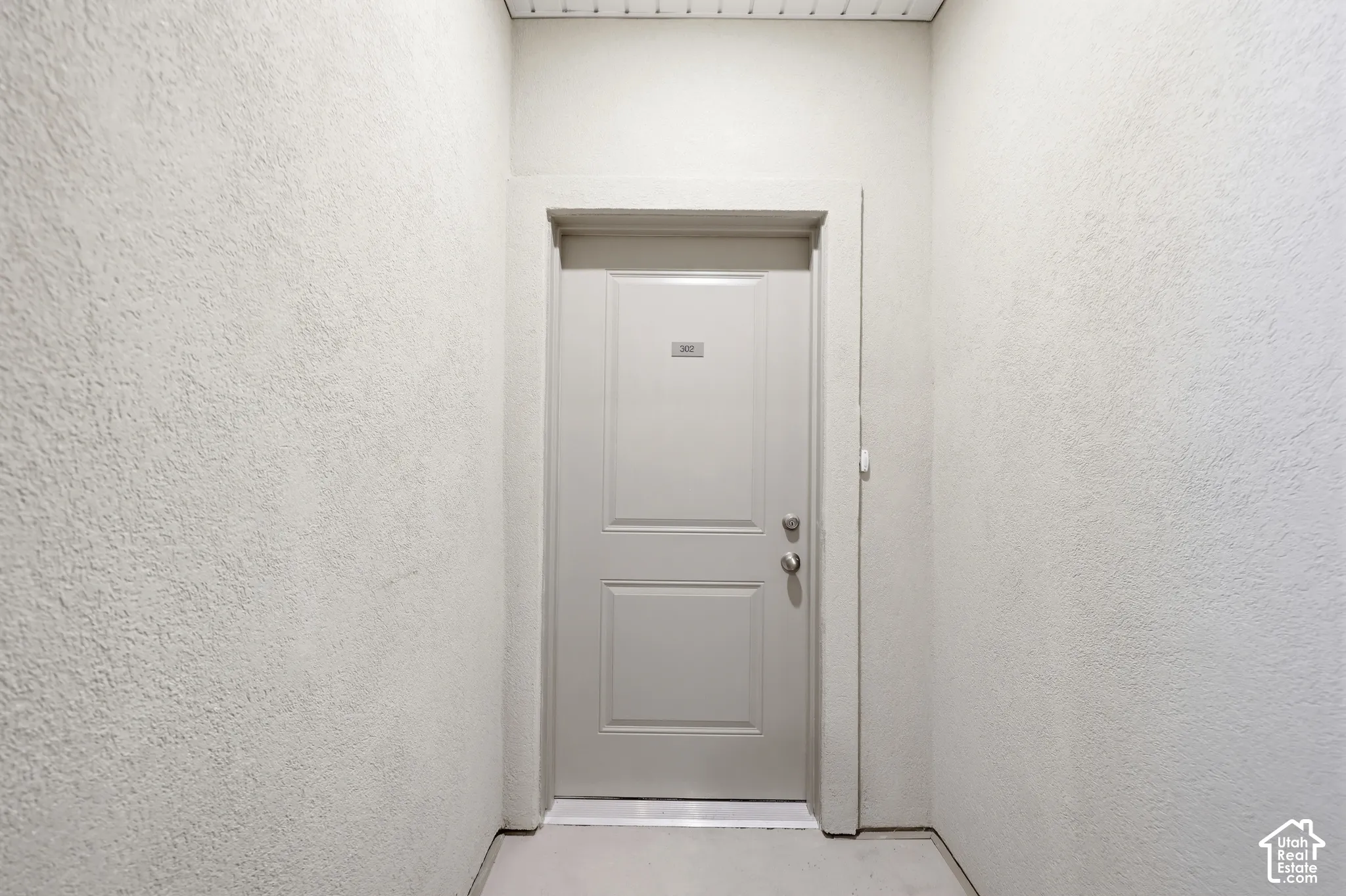 Solid-core paneled entry door featuring a brushed metal deadbolt and handle set, encased in smooth-finish trim within a textured wall surround