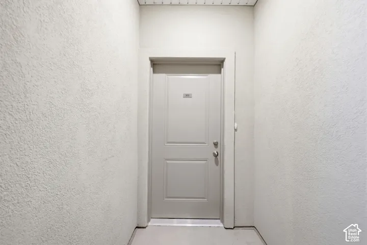 Solid-core paneled entry door featuring a brushed metal deadbolt and handle set, encased in smooth-finish trim within a textured wall surround
