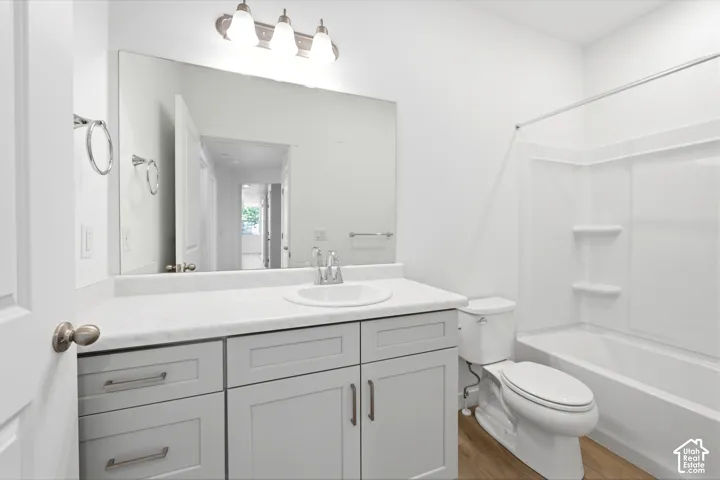 Bathroom featuring a gray vanity with an integrated basin, stone-composite countertop, full-width vanity mirror, three-light fixture, and a tub-shower combination with built-in shelving