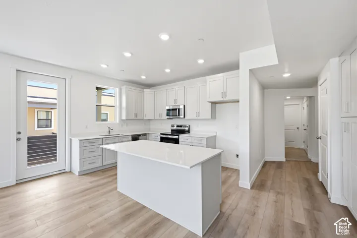 Kitchen featuring white cabinetry, quartz countertops, a central island, recessed lighting, and wood-finish flooring
