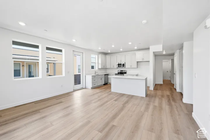Kitchen featuring white cabinetry, solid-surface countertops, stainless steel appliances, recessed lighting, and wood-finish flooring