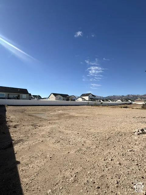 Expansive unimproved lot featuring a white vinyl privacy fence and mountain backdrop