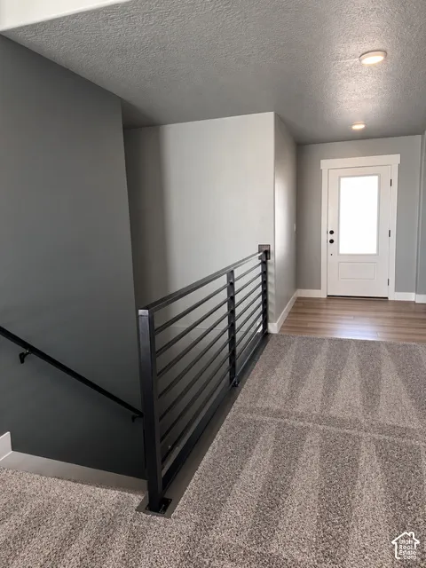 Modern horizontal metal stair railing featuring a matte black finish, light wood-finish flooring, and recessed ceiling lighting