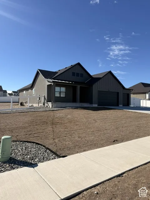 Modern farmhouse exterior featuring vertical board-and-batten siding, a multi-gabled roofline, three-car garage, and concrete driveway