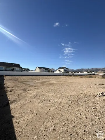 Expansive unimproved lot featuring a white vinyl privacy fence and mountain backdrop