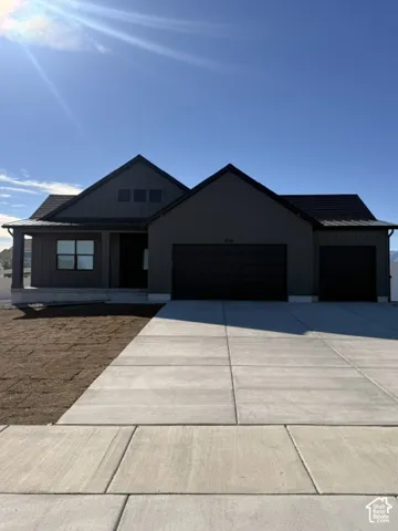 Single-story exterior featuring dark vertical siding, dual-pitched rooflines, a covered front porch, and a three-car garage with a concrete driveway