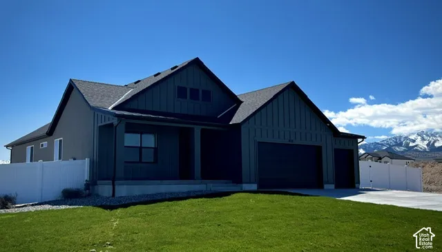 Modern exterior featuring vertical board-and-batten siding, asphalt shingle roofing, attached three-car garage, and concrete driveway