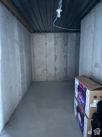 Storage area featuring unfinished poured concrete walls, a concrete floor, and exposed metal ceiling decking