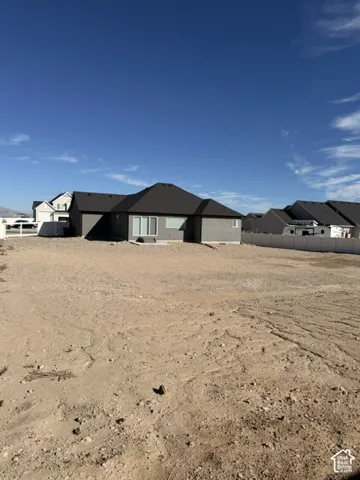 Expansive backyard featuring a gravel surface, perimeter vinyl fencing, and a concrete patio