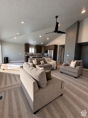 Vaulted ceilings featuring recessed lighting and a matte black ceiling fan, complemented by dark wood cabinetry and neutral carpeting