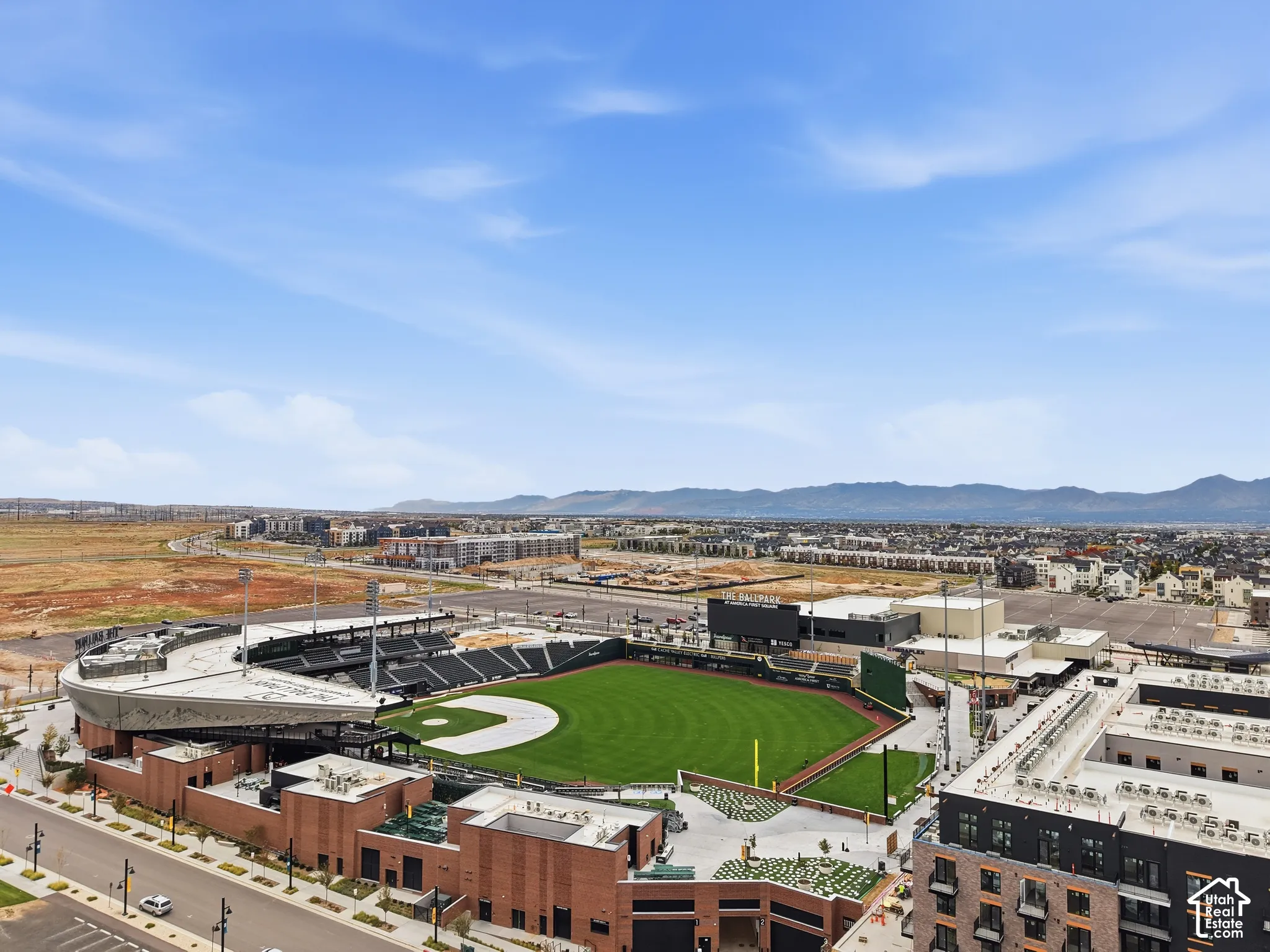 Aerial perspective of a multi-purpose stadium featuring brick masonry construction, professional turf field, stadium lighting, and expansive mountain scenery