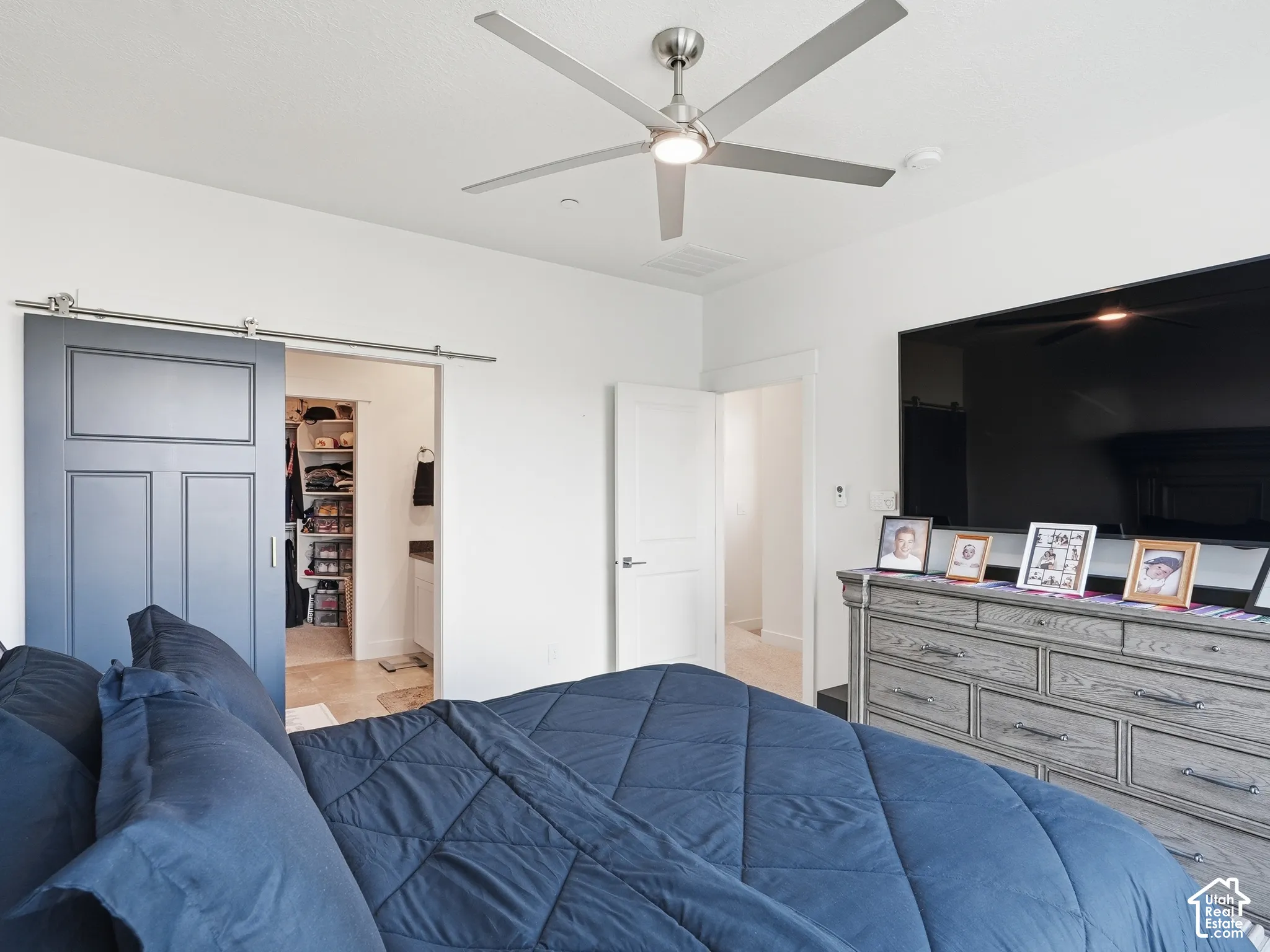 Charcoal-finished sliding barn door, brushed-nickel five-blade ceiling fan with integrated lighting, and white interior swing door