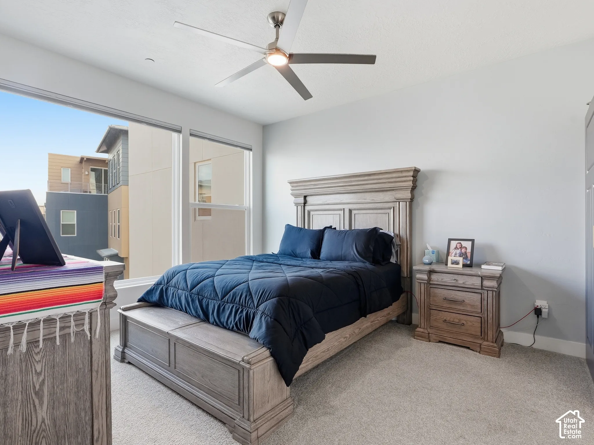Neutral wall tones, carpeted flooring, and a contemporary ceiling fan with integrated lighting