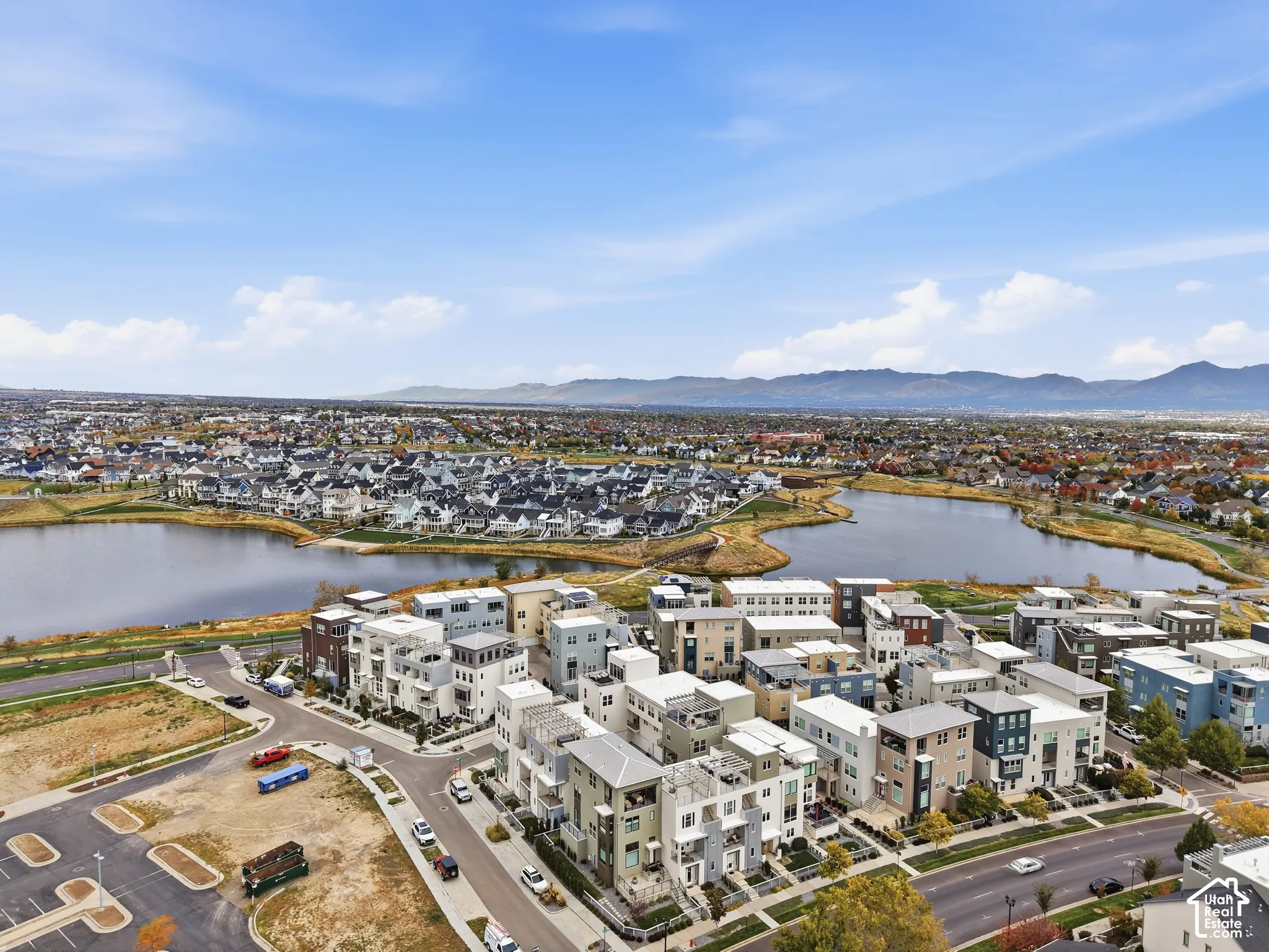 Aerial perspective featuring multi-story residential architecture, proximity to a large water feature, and a prominent mountain range backdrop