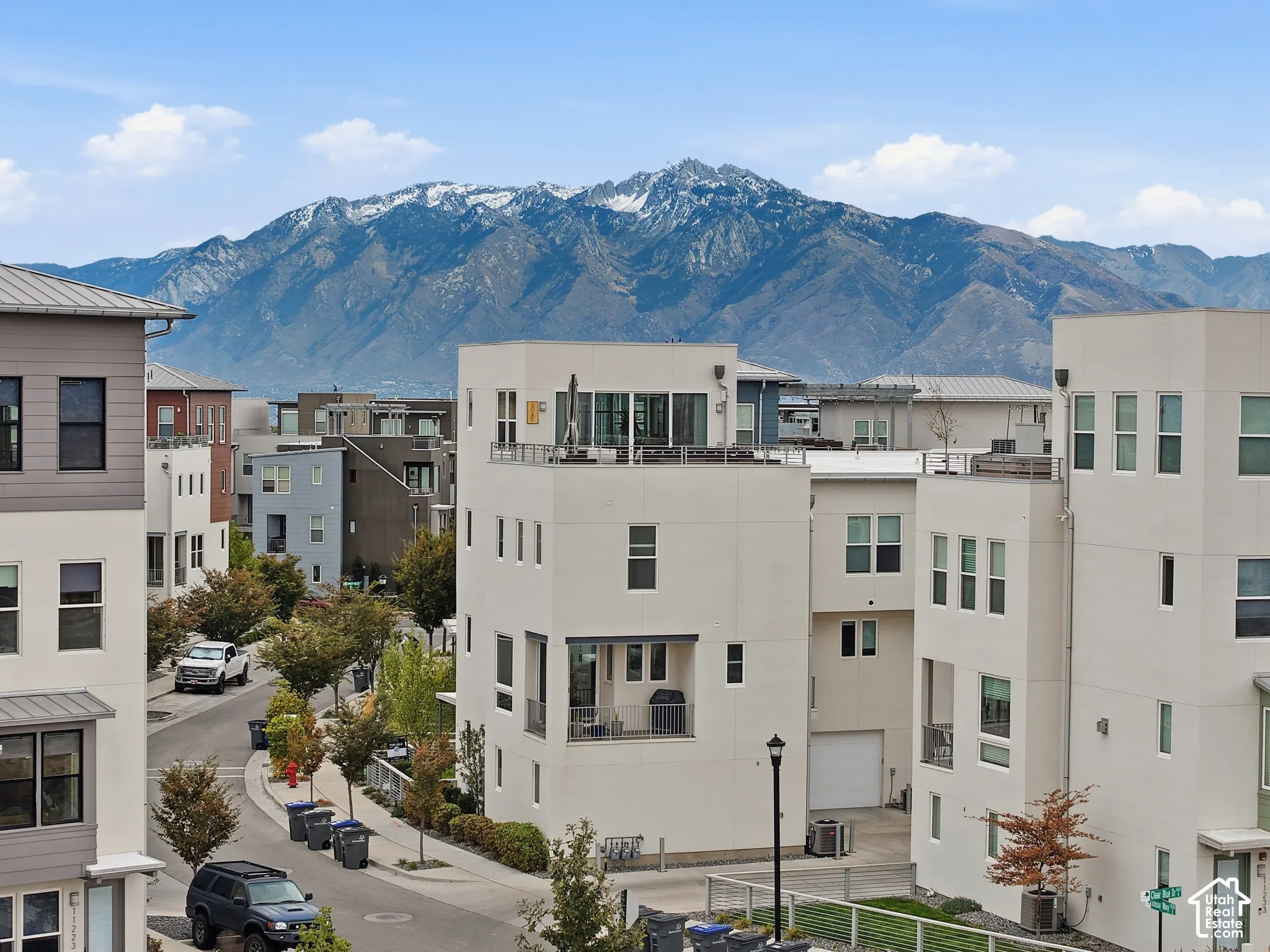 Modern multi-story structures featuring stucco exteriors, flat roofing, expansive rooftop terraces, and mountain backdrops