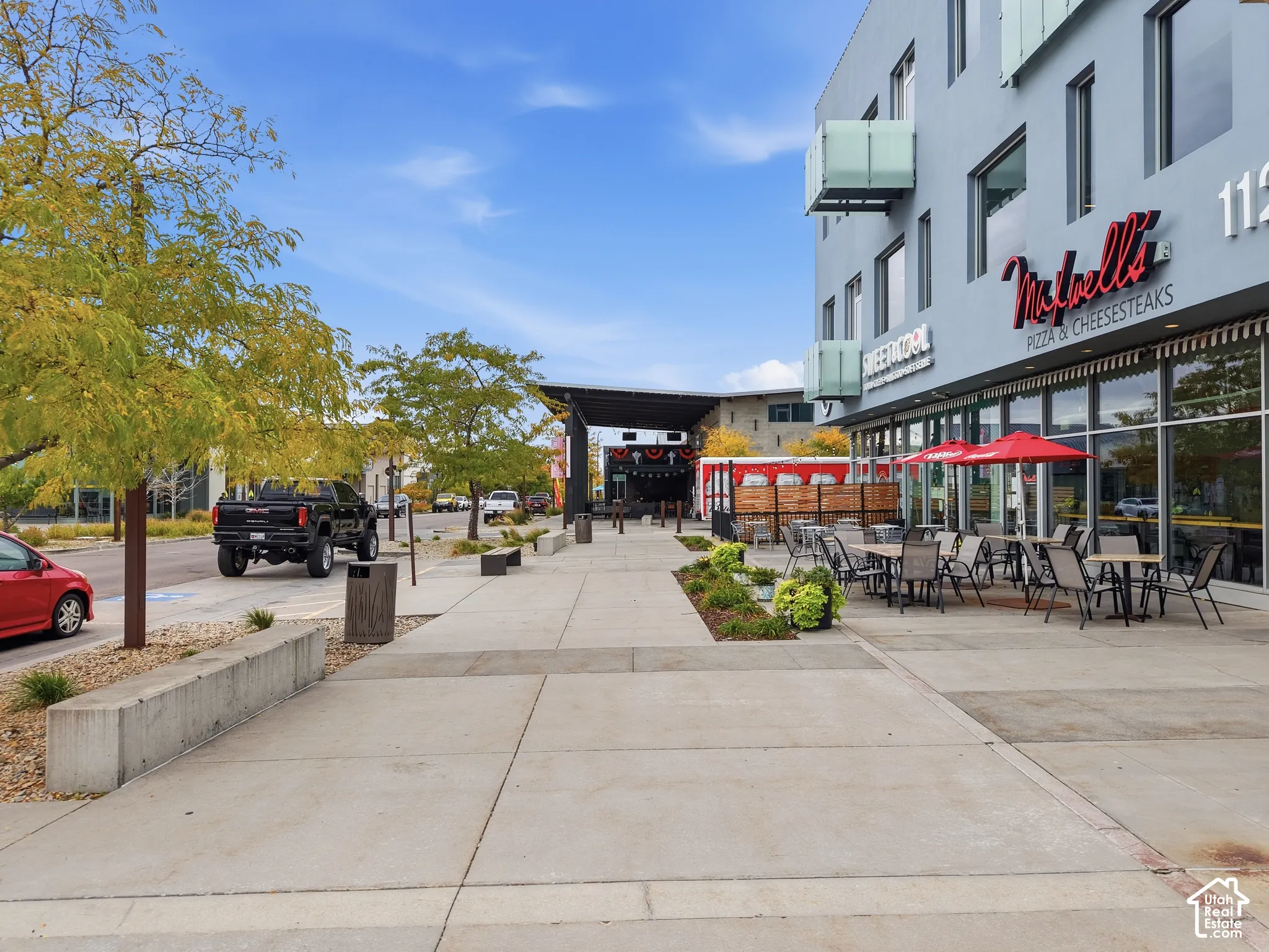 Modern commercial building featuring expansive glass storefronts, concrete pedestrian walkways, cantilevered balcony structures, and integrated landscaping