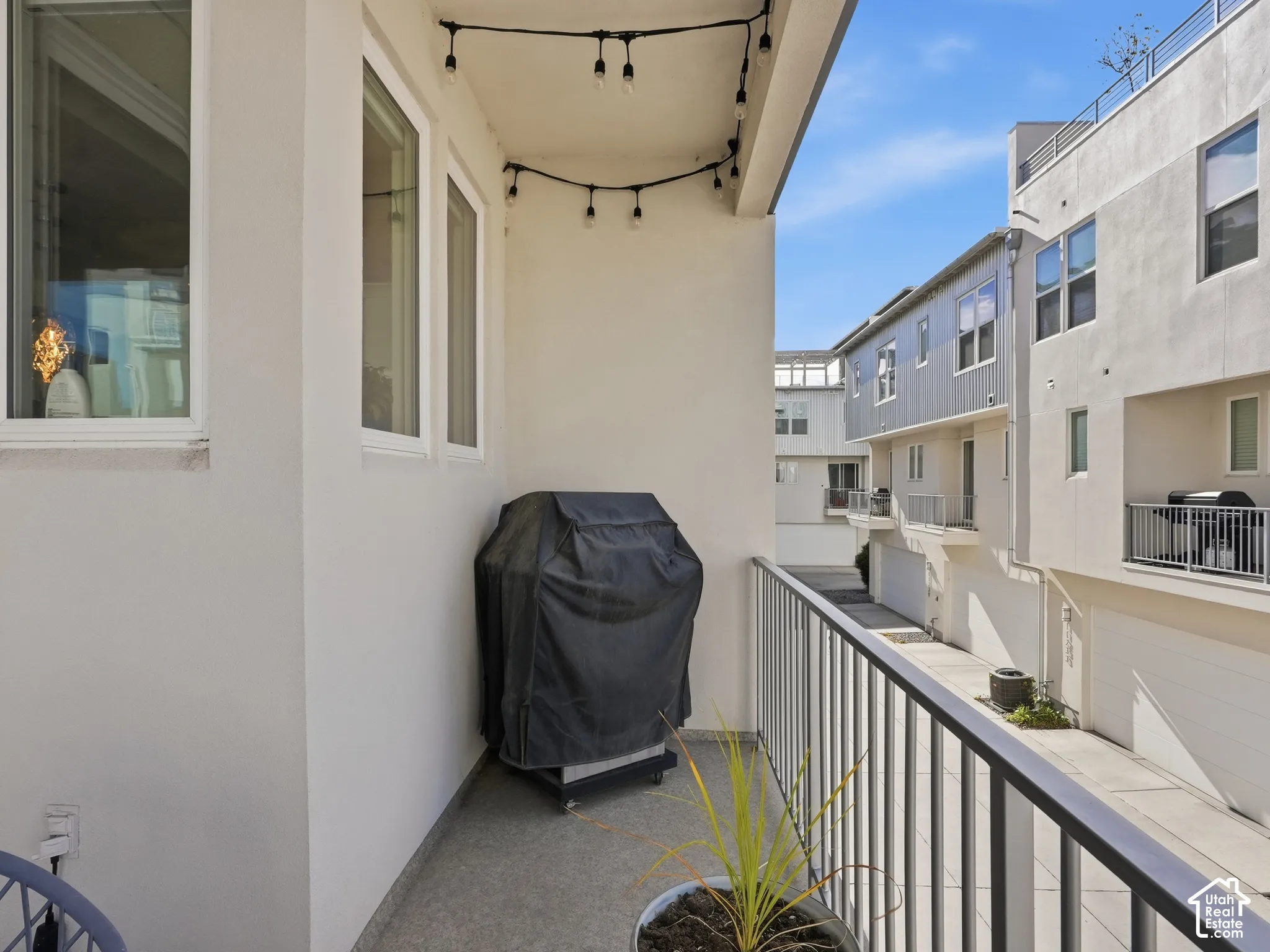 Covered balcony featuring concrete flooring, white stucco walls, and metal railings