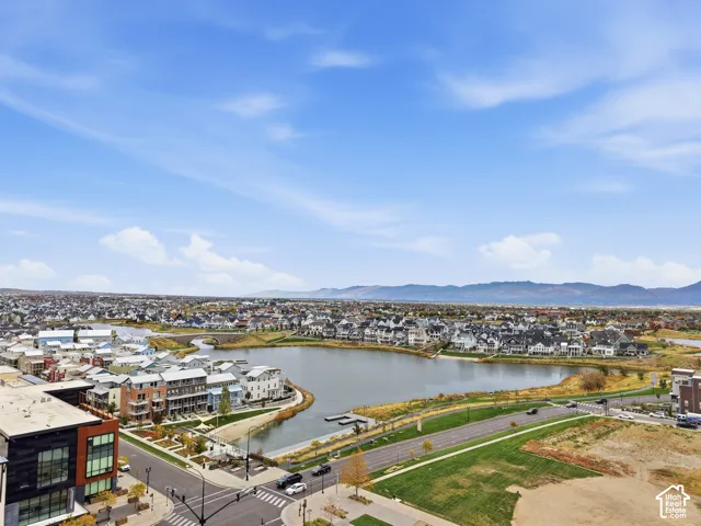 Aerial perspective overlooking a community lake, paved roads, and mountain backdrop