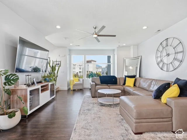 Living area featuring dark wood-finish flooring, recessed lighting, a modern ceiling fan, and large windows