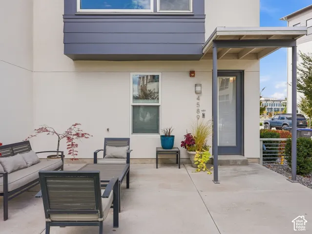 Concrete patio featuring a metal-framed entryway cover, vertical siding accents, and modern glass-panel door