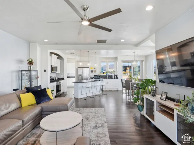 Open-concept interior featuring dark wood-finish flooring, a kitchen island with stone countertop, recessed lighting, and a modern ceiling fan