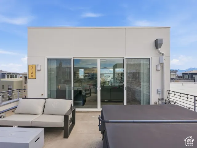 Rooftop deck featuring a concrete surface, metal railing with integrated string lighting, and sliding glass door entry
