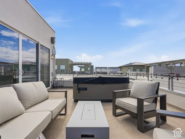 Rooftop terrace featuring a concrete surface, built-in hot tub, metal cable railing, and sliding glass doors
