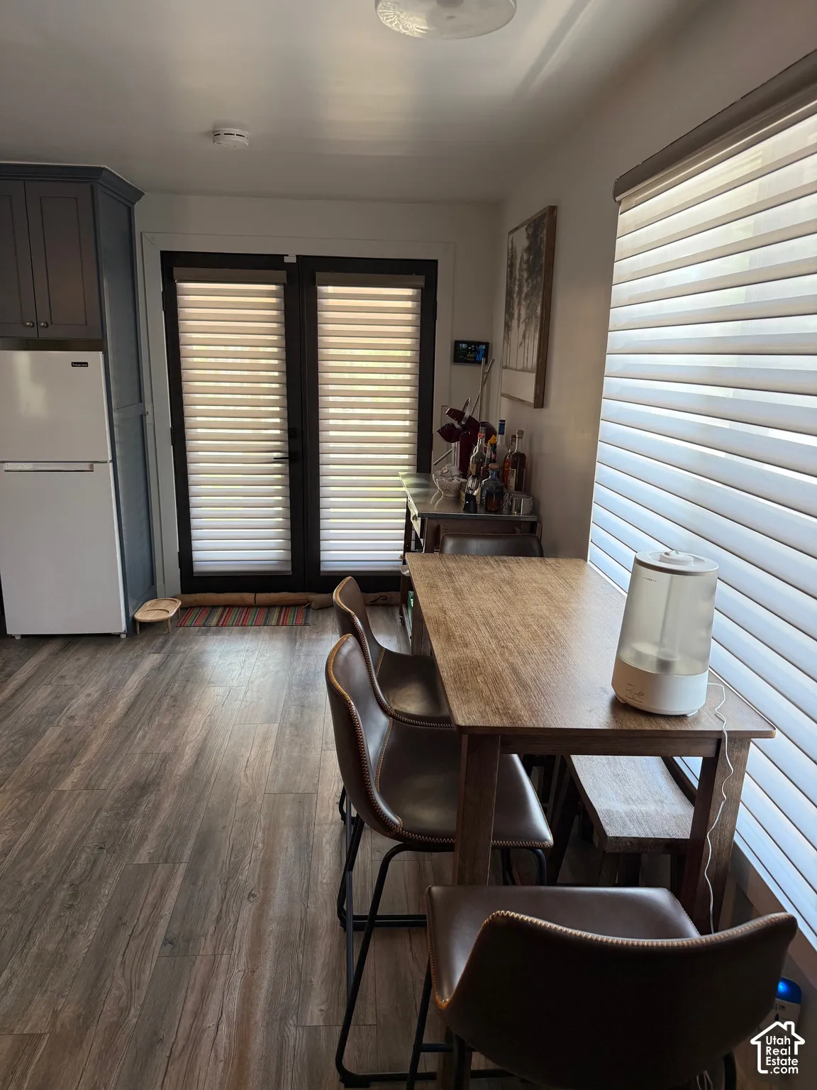 Dark cabinetry, wood-finish flooring, and double glass-paned doors featuring integrated blinds